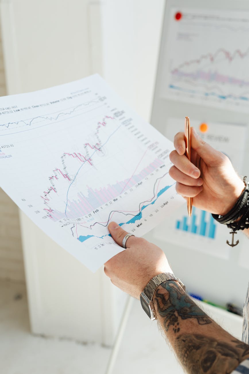 a person holding pen and paper with graphs